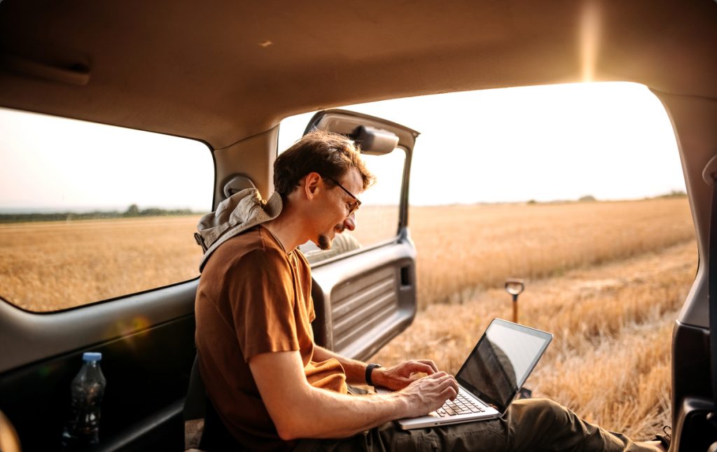 guy looking at laptop in field