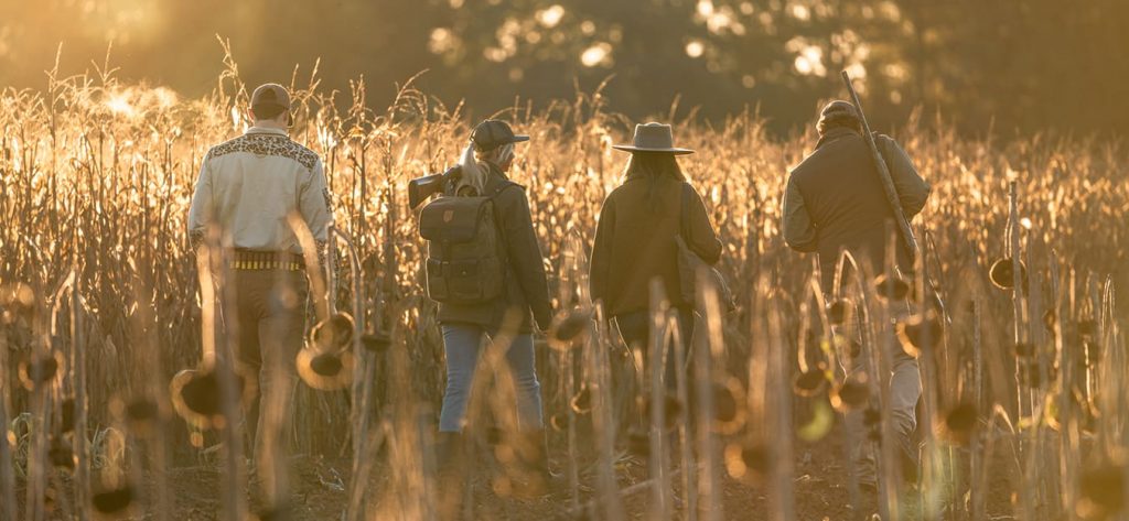 Men and women hunting in field.