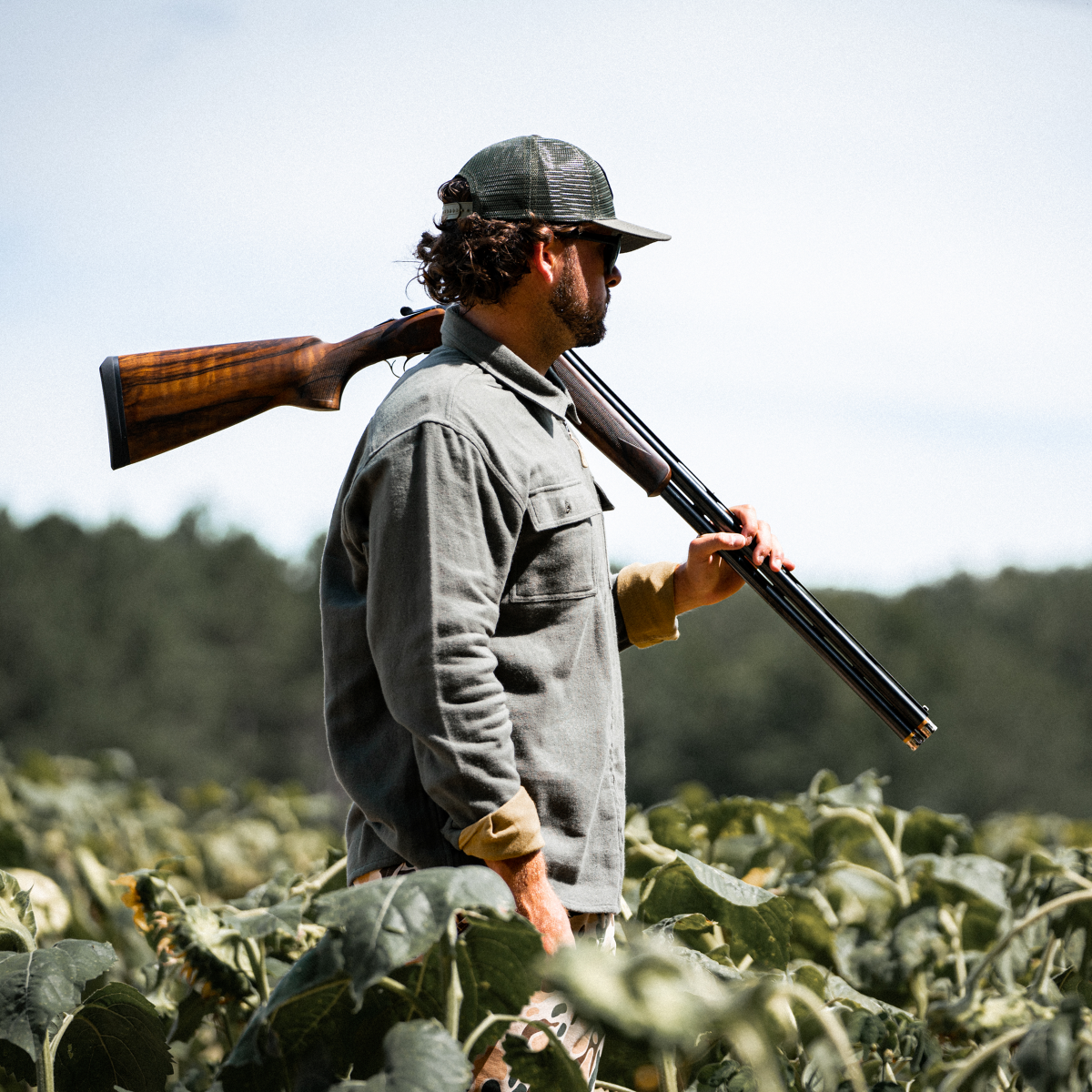 Firearms-Hunting_Brand Guy walking through field with shotgun on shoulder